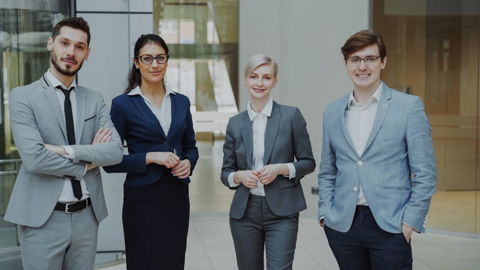 Four business professionals posing confidently in a modern office environment